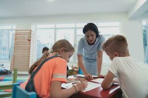 Créatif des gamins pendant un art classe dans une garderie centre ou élémentaire école salle de cours dessin avec femelle professeur. photo