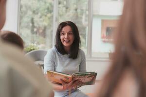 en train de lire temps dans un élémentaire école ou Jardin d'enfants, une prof lit une livre à les enfants dans un élémentaire école ou Jardin d'enfants. le concept de préscolaire éducation. sélectif concentrer photo