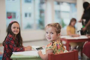 Créatif des gamins séance dans une préscolaire institution, dessiner et avoir amusement tandis que elles ou ils avoir un éducation photo