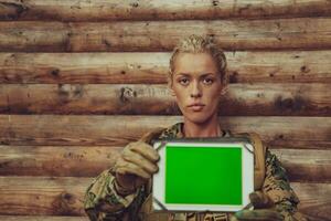 femme soldat en utilisant tablette ordinateur contre vieux en bois mur dans camp photo