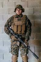 une soldat dans uniforme des stands dans de face de une pierre mur dans plein guerre équipement en train de préparer pour bataille photo