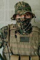 une soldat dans uniforme des stands dans de face de une pierre mur dans plein guerre équipement en train de préparer pour bataille photo
