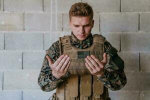 une musulman soldat de le spécial les forces prie à Dieu par élevage le sien mains et départs une prière photo