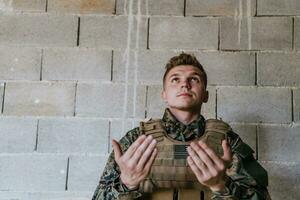 une musulman soldat de le spécial les forces prie à Dieu par élevage le sien mains et départs une prière photo