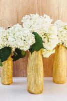 bouteilles à paillettes dorées avec hortensia. fleurs blanches dans des vases en or
