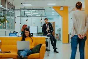 Beau femme d'affaires employé séance sur une Jaune canapé tandis que travail sur sa portable dans Commencez entreprise. photo