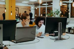 deux collègues travail sur une projet dans moderne Commencez des bureaux. gars avec afro la Coupe de cheveux et une femelle blond employé travail à le bureau. photo