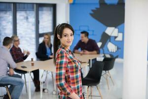 portrait de jeune femme d'affaires au bureau avec l'équipe en arrière-plan photo