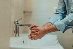 homme en utilisant savon et la lessive mains en dessous de le l'eau robinet. hygiène concept main fermer détail. photo