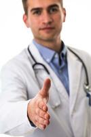 portrait de une médecin en portant en dehors le sien main comme une soutien à une patient isolé sur une blanc Contexte photo