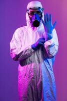 coronavirus covid-19 pandémie. médecin scientifique portant protecteur biologique costume et masque dû à global soins de santé épidémie avertissement et danger Contexte dans bleu et rose néon lumières Contexte. photo