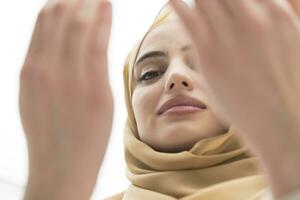 portrait de magnifique musulman femme dans à la mode robe avec hijab fabrication traditionnel prière à Dieu garde mains dans prier geste isolé sur blanc Contexte photo