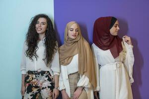 groupe portrait de magnifique musulman femmes deux de leur dans une à la mode robe avec hijab isolé sur une coloré Contexte photo