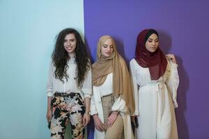groupe portrait de magnifique musulman femmes deux de leur dans une à la mode robe avec hijab isolé sur une coloré Contexte photo