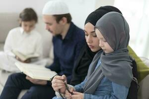 traditionnel musulman famille Parents avec les enfants en train de lire coran et prier ensemble sur le canapé avant iftar dîner pendant une Ramadan le banquet à Accueil photo