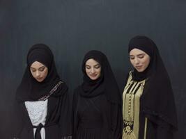 groupe portrait de magnifique musulman femmes dans une à la mode robe avec hijab isolé sur noir Contexte photo