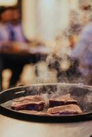 fermer photo de délicieux Viande étant grillé. dans le arrière-plan, copains et famille sont séance et attendre pour une repas