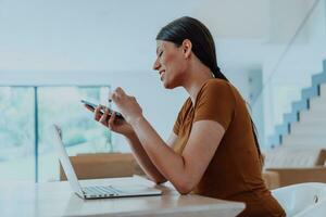 femme séance dans vivant pièce en utilisant portable et téléphone intelligent Regardez à came parler par vidéo appel avec affaires ami parents, tête tir. emploi entretien répondre des questions. photo