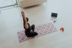 Jeune magnifique femelle faire de l'exercice, élongation et pratiquant yoga avec entraîneur via vidéo appel conférence dans brillant ensoleillé maison. en bonne santé mode de vie, bien-être et pleine conscience concept. photo