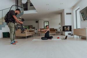 derrière le scène. photo de une cameraman enregistrement une femme Faire yoga des exercices à un en ligne formation tandis que en utilisant et en train de regarder une portable