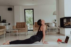 Jeune magnifique femelle faire de l'exercice, élongation et pratiquant yoga avec entraîneur via vidéo appel conférence dans brillant ensoleillé maison. en bonne santé mode de vie, bien-être et pleine conscience concept. photo