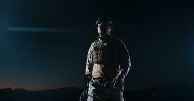 armée soldat dans combat uniformes avec un agression fusil, assiette transporteur et combat casque Aller sur une dangereux mission sur une pluvieux nuit. photo