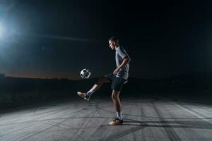 portrait de une Jeune Beau football joueur homme sur une rue en jouant avec une Football balle. photo