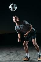 portrait de une Jeune Beau football joueur homme sur une rue en jouant avec une Football balle. photo