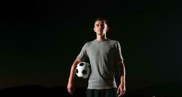 portrait de une Jeune Beau football joueur homme sur une rue en jouant avec une Football balle. photo