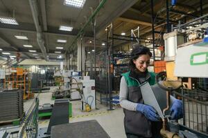 une femme travaillant dans une usine métallurgique moderne assemble des pièces pour une nouvelle machine photo