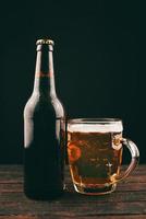 Photo verticale de verre à bière et bouteille sur fond sombre