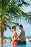 un jeune couple heureux se détend et prend une boisson fraîche au bord de la piscine photo