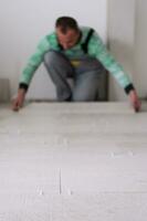 travailleur installant les carreaux en céramique effet bois sur le sol photo