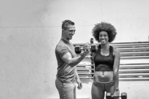 femme noire faisant des boucles de biceps avec un entraîneur de fitness photo