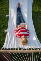 femme lisant un livre tout en se relaxant sur un hamac photo