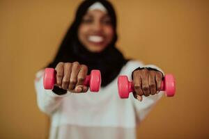 femme musulmane afro favorise une vie saine, tenant des haltères dans ses mains photo