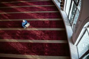 homme musulman priant allah seul à l'intérieur de la mosquée et lisant le livre de houx islamique photo