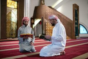 deux musulmans dans la mosquée lisant le coran ensemble concept d'éducation islamique photo