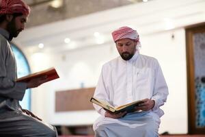 deux musulmans dans la mosquée lisant le coran ensemble concept d'éducation islamique photo