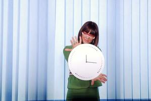 .une jolie femme d'affaires se cachant derrière une horloge photo