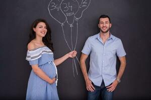 Couple enceinte dessinant leur imagination sur tableau noir photo