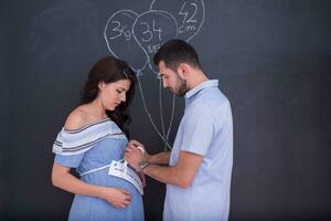 Couple enceinte dessinant leur imagination sur tableau noir photo