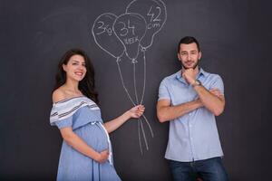Couple enceinte dessinant leur imagination sur tableau noir photo