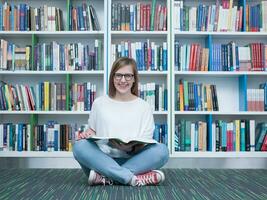 étudiant fille en train de lire livre dans bibliothèque photo