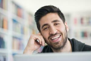 étudiant à la bibliothèque de l'école utilisant un ordinateur portable pour la recherche photo