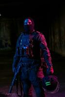 armée soldat dans combat uniformes avec un agression fusil et combat casque nuit mission foncé Contexte. bleu et violet gel lumière effet. photo