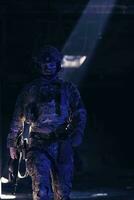 armée soldat dans combat uniformes avec un agression fusil et combat casque nuit mission foncé Contexte. bleu et violet gel lumière effet. photo