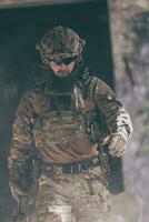 un soldat barbu en uniforme des forces spéciales traverse un bâtiment abandonné après une mission réussie. mise au point de la sélection photo