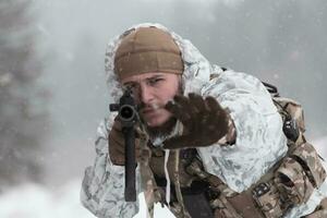 guerre d'hiver dans les montagnes arctiques. opération dans des conditions froides.soldat en uniforme camouflé d'hiver dans l'armée de guerre moderne un jour de neige sur le champ de bataille de la forêt avec un fusil. mise au point sélective photo