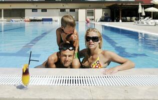 une jeune famille heureuse s'amuse à la piscine photo